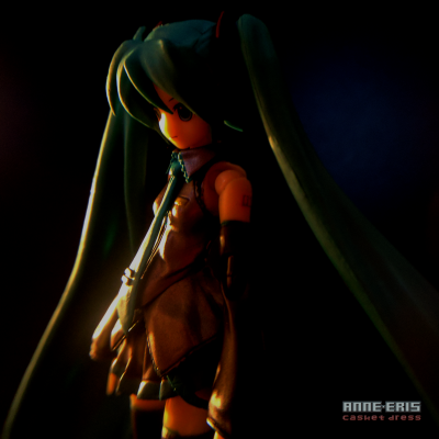 Smiling Hatsune Miku doll looking to the left, she is lit by a warm, soft light.