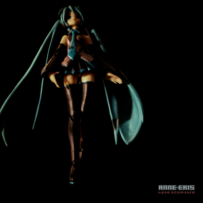 Low angle shot of a dramatically lit Hatsune Miku Doll hovering against a black background.